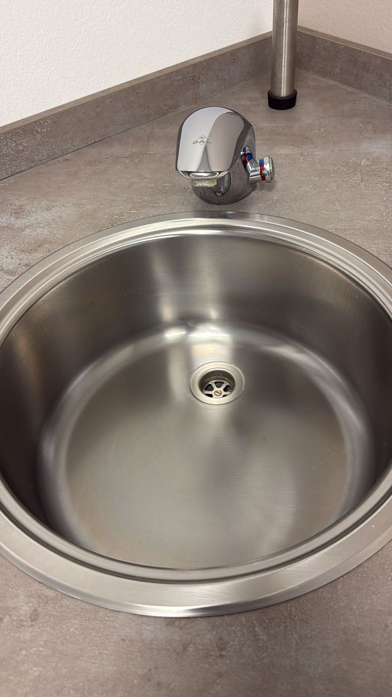 Glänzend gereinigtes Edelstahl-Waschbecken mit polierter Armatur in einer Teeküche