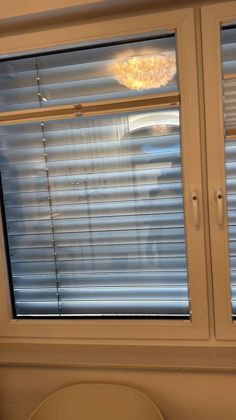 Sauber gereinigtes Fenster mit Jalousie nach der Glasreinigung